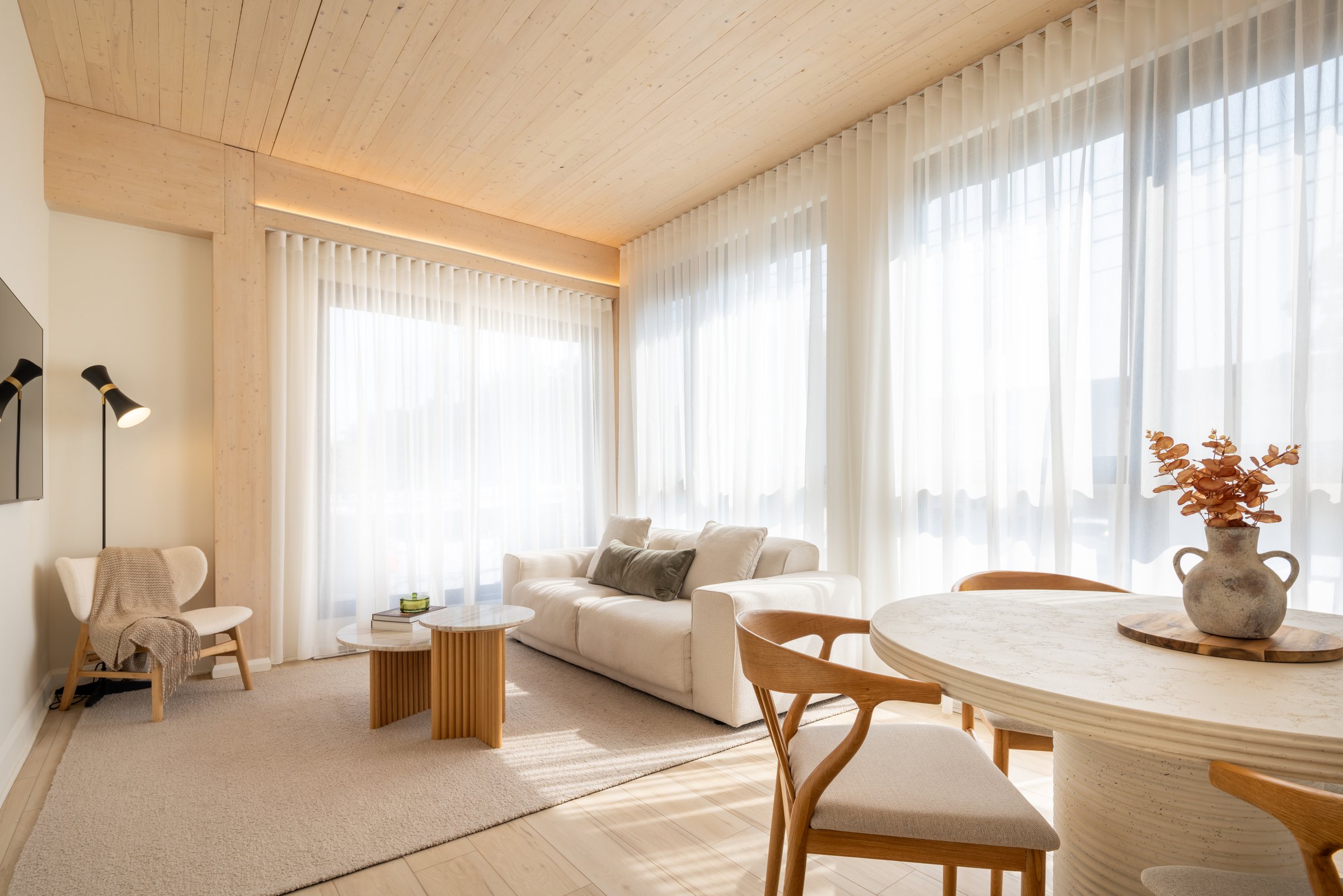 Le salon du logement modèle d'ANDAS, plafond en bois massif et deux murs de fenêtres